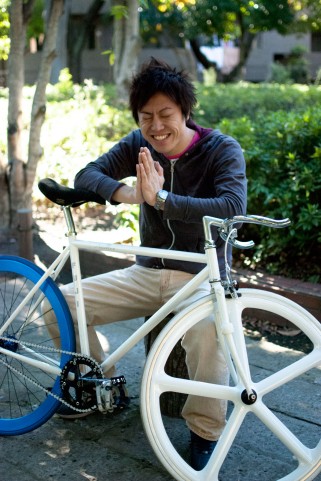 自転車の前で手を合わせて笑う男性